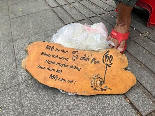 Bảng hiệu "cửa hàng" của mệ Hường được đặt dưới nền đất vỉa hè.