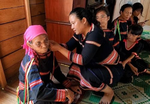 Người con dâu đeo trang sức truyền thống cho bà Ksor H’Lang để bày tỏ lòng biết ơn và mong cầu bình an cho đấng sinh thành. Ảnh: M.C