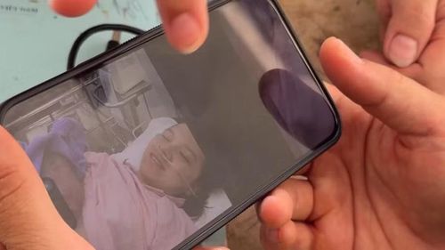 Trung tá Nguyễn Xuân Quýnh ngắm nhìn hình ảnh vợ và con trai qua màn hình điện thoại của Trung tá, bác sĩ Vũ Thu Thủy. Ảnh: Mỹ Hà