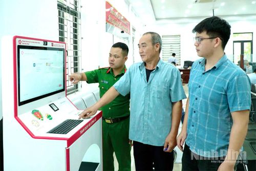 Cán bộ xã Rạng Đông hướng dẫn người dân sử dụng Kiosk hành chính công thông minh.