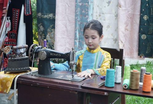 Bạn nhỏ tìm hiểu về không gian may đo áo dài Huế xưa. Ảnh: S.Thùy