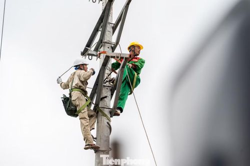 Các công nhân khác đang tích cực kéo lại dây điện bị đứt tại các cột điện đã được thi công dựng lại.