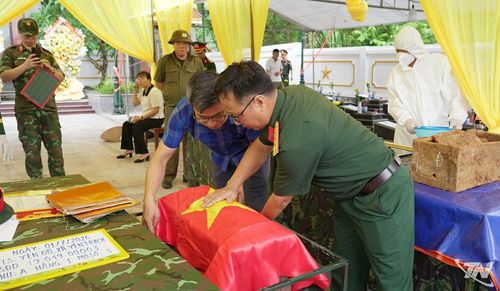 Lực lượng Quân sự và cán bộ Sở Nội vụ cẩn trọng phủ Quốc kỳ lên tiểu sành đựng hài cốt liệt sĩ trước khi thực hiện nghi thức hoàn mộ.