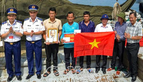 Cảnh sát biển Việt Nam tặng cờ Tổ quốc, ảnh Bác Hồ và quà cho ngư dân hoạt động trên vùng biển do Trạm Cảnh sát biển số 4 quản lý. (Ảnh đơn vị cung cấp)