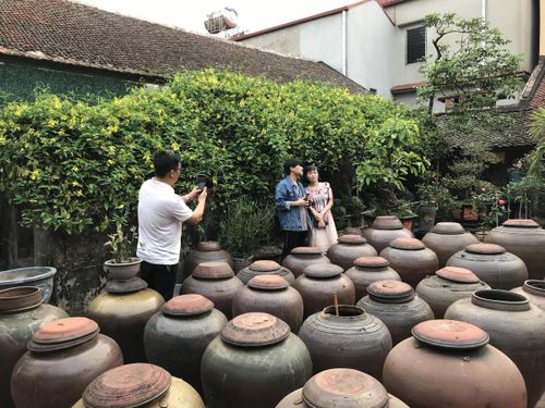 Du khách chụp ảnh lưu niệm tại một ngôi nhà cổ trong làng Đường Lâm (Hà Nội). Ảnh: Hoàng Thu Phố