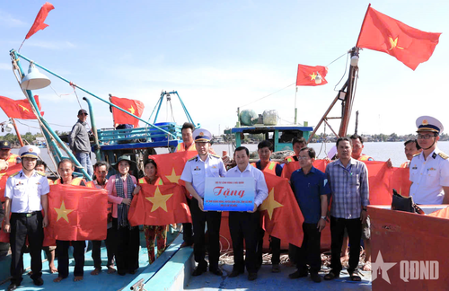 Đại tá Hoàng Quốc Hoàn, Phó chính ủy Vùng 5 Hải quân trao cờ Tổ quốc tặng ngư dân tỉnh Cà Mau. Ảnh: VĂN ĐỊNH