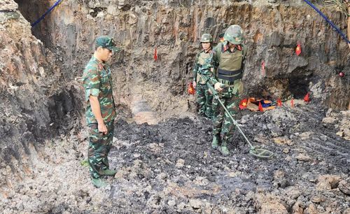 Cán bộ chiến sĩ dùng máy để dò tìm bom mìn có thể còn sót lại trong lớp đất, trước khi đào tìm kiếm, quy tập hài cốt liệt sĩ.