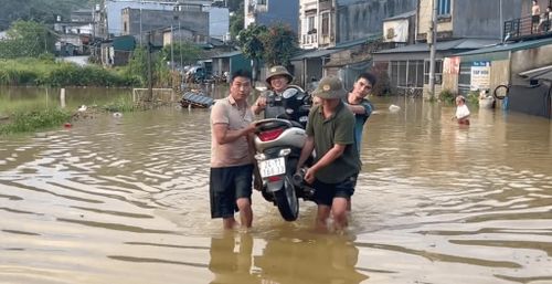 Người dân phải khiêng đồ khỏi nơi ngập nước do mưa.