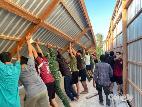 Cán bộ, chiến sĩ Đồn Biên phòng Đất Mũi cùng người dân dựng lại nhà cho chị Quỳnh ổn định cuộc sống.
