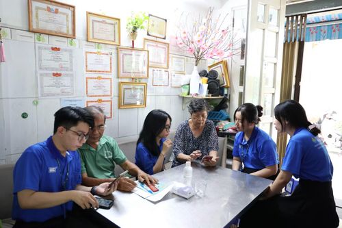Sinh viên Sư phạm hỗ trợ các cô chú sử dụng app Sổ tay đảng viên điện tử. Ảnh: Ngô Tùng