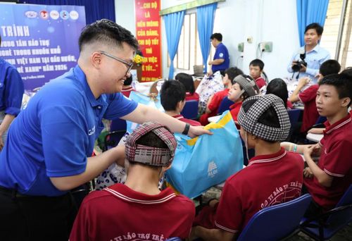 Các bạn du học sinh cùng đoàn viên thanh niên thành phố gửi tặng bạn nhỏ ở trung tâm những món quà ấm tình. Ảnh: Ngô Tùng