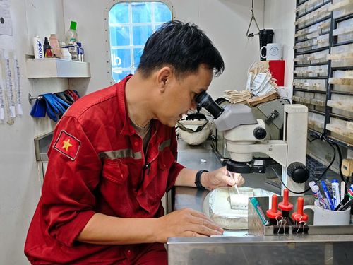Kỹ sư Phạm Quốc Minh đang kiểm tra mẫu lấy từ giếng khoan.