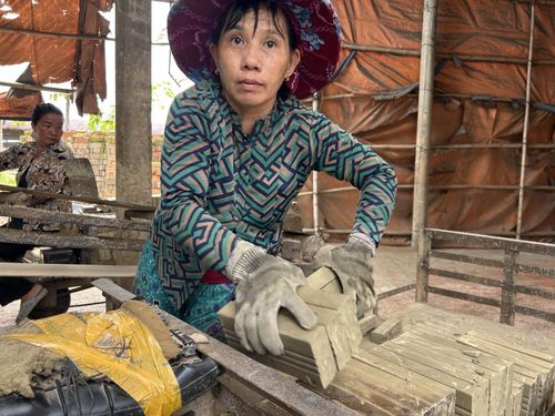 Những người phụ nữ chịu trách nhiệm vận chuyển gạch đã phơi đến lò rồi cho gạch lên băng chuyền để đưa vào lò.