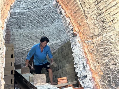 Bên trong lò, những người đàn ông tiếp nhận, sắp xếp những viên gạch ngay ngắn chuẩn bị cho quá trình nung. Gạch được nung bằng trấu. Để có viên gạch đạt chuẩn, đỏ au thì người thợ phải canh lửa rất cẩn trọng.