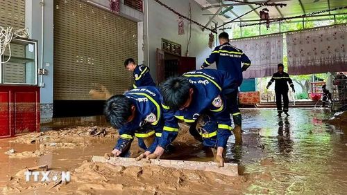 Lực lượng Cảnh sát phòng cháy chữa cháy và cứu nạn cứu hộ, Công an tỉnh Sơn La hỗ trợ người dân xã Mường La gạt bùn đất do mưa lớn trôi vào nhà. (Ảnh: TTXVN phát)