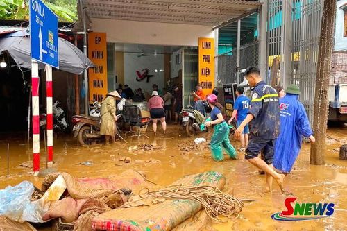 Cán bộ, chiến sĩ và lực lượng tại chỗ hỗ trợ người dân dọn bùn đất, vệ sinh nhà cửa sau ngập úng.