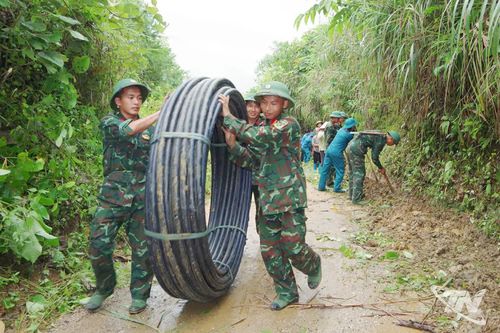 Cán bộ, chiến sĩ vận chuyển ống nước phục vụ thi công.