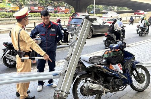 Cán bộ Đội Cảnh sát giao thông số 7 (Phòng Cảnh sát giao thông Công an thành phố Hà Nội) kiểm tra xe máy chở hàng hóa cồng kềnh trên đường Khuất Duy Tiến. Ảnh: Trung Nguyên - TTXVN