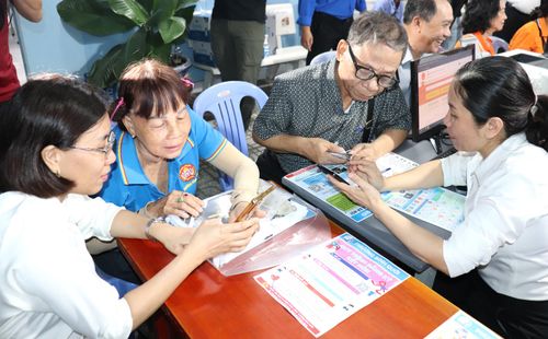 Cán bộ tổ địa bàn số phường Bình Quới hướng dẫn người cao tuổi sử dụng các ứng dụng trên điện thoại di động ngay tại khu dân cư (ẢNH: THÁI PHƯƠNG)