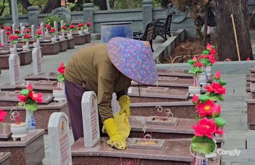Người phụ nữ lặng lẽ lau lớp bụi trên bia mộ tại Nghĩa trang Liệt sĩ Quốc gia Trường Sơn