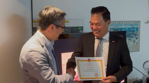 Đại sứ Việt Nam tại Canada Phạm Vinh Quang (trái) trao giấy khen cho một thành viên Hội Canada Việt Nam vì có thành tích đóng góp xuất sắc