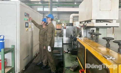 Anh Huỳnh Minh Cảnh cùng đồng nghiệp kiểm tra máy móc tại xưởng của Công ty TNHH Gia công đồng Hải Lượng.