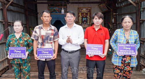 Đồng chí Trương Văn Ty, Phó Bí thư Thường trực Đảng ủy xã Đất Mũi, trao bảng tượng trưng hỗ trợ nhà cho các hộ gia đình.
