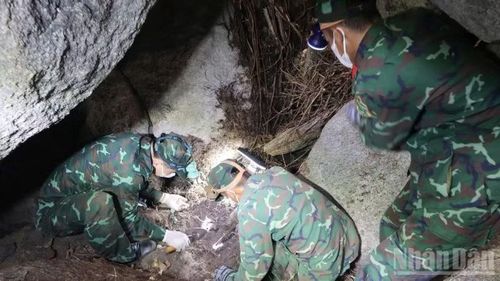 Cán bộ, chiến sĩ cẩn trọng gỡ từng phiến đá dưới hang sâu để tìm hài cốt liệt sĩ.