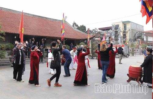 Các thành viên cao tuổi cùng lớp kế cận của phường Xoan An Thái hướng dẫn du khách nước ngoài trải nghiệm hát Xoan tại Đình Hùng Lô.