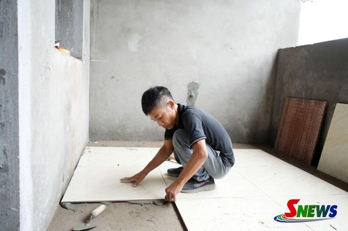 Công nhân thi công lát gạch nền các phòng nội trú.