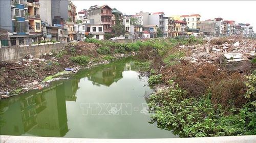 Rác thải sinh hoạt và rác thải xây dựng chồng chất lên nhau ở hai ven bờ sông Nhuệ. Ảnh: Kim Anh/TTXVN