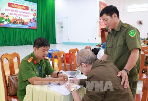 Thân nhân liệt sĩ được lực lượng công an hỗ trợ thủ tục để lấy mẫu sinh phẩm ADN. Ảnh: Nhựt An - TTXVN