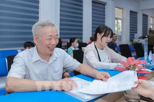 Ông Nguyễn Xuân Phong (70 tuổi, Quốc Oai) chia sẻ niềm vui và hạnh phúc khi được cán bộ Trung tâm Phục vụ hành chính công Hà Nội hỗ trợ nhiệt tình, chu đáo trong quá trình thực hiện thủ tục tại đơn vị. Ảnh: Phan Phương - TTXVN 
