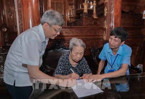 Cụ Đỗ Thị Điềm (91 tuổi), vợ liệt sĩ tại thôn Ngọc Bài, rất phấn khởi khi được Tổ xung kích (Chi nhánh 07, Trung tâm Phục vụ hành chính công Hà Nội) hỗ trợ tận nhà hoàn thiện thủ tục ủy quyền nhận trợ cấp. Ảnh: Phan Phương - TTXVN