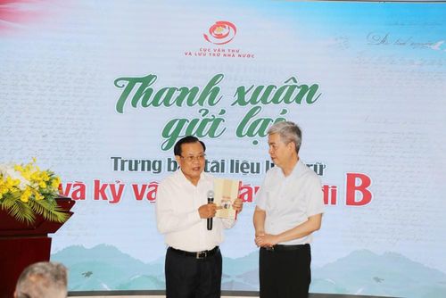 Đồng chí Phạm Quang Nghị - nguyên Ủy viên Bộ Chính trị, nguyên Bí thư Thành ủy Hà Nội - trao tặng đại diện Cục Văn thư và Lưu trữ Nhà nước cuốn sách "Nơi ấy là chiến trường" của ông