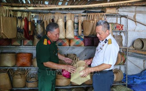 Thương binh Vũ Xuân Túy (áo xanh) chia sẻ về quá trình tạo ra sản phẩm thủ công mỹ nghệ bằng cói.