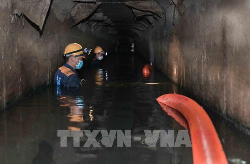 Ngâm mình dưới dòng nước đen ngòm để hút sạch bùn thải, khơi thông dòng chảy cho Thủ đô. Ảnh: Phan Phương – TTXVN