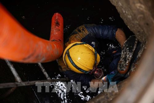 Công nhân Công ty TNHH MTV Thoát nước Hà Nội trực tiếp xuống cống ngầm thu gom rác để vận chuyển về khu tập kết xử lý. Ảnh: Tiến Long/TTXVN phát