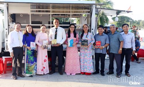 Các đại biểu chụp hình lưu niệm tại xe thư viện lưu động.