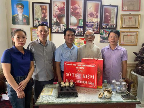 Ông Uông Văn Hường nhận sổ tiết kiệm và quà tri ân từ đoàn công tác xã Ô Diên. Ảnh: Đinh Hiền