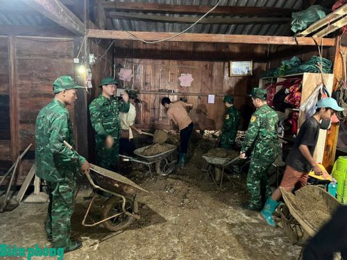 Cán bộ, chiến sĩ Đồn Biên phòng Sin Suối Hồ hỗ trợ các gia đình dọn dẹp đất đá sạt lở tràn vào nhà. Ảnh: Biên Cương