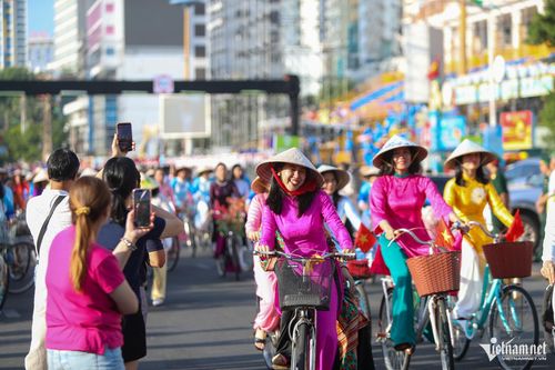 Người dân hai bên đường tỏ ra thích thú, dùng điện thoại ghi lại cảnh đoàn diễu hành mặc áo dài đạp xe đi qua. Ảnh: Xuân Ngọc