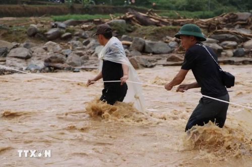 Nước lũ nhiều chỗ vẫn chảy xiết, lực lượng cứu hộ phải căng dây để hỗ trợ người dân di chuyển an toàn. (Ảnh: Nguyễn Oanh/TTXVN)