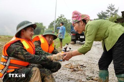 Người dân xã Mường Than chia sẻ nước uống cùng lực lượng cứu hộ. (Ảnh: Nguyễn Oanh/TTXVN)