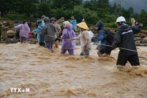 Người dân bám dây qua suối để đi đưa tang người đã mất. (Ảnh: Nguyễn Oanh/TTXVN)