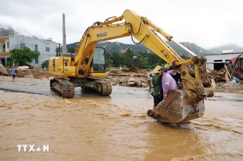 Lũ dần rút, người dân qua suối bằng máy xúc. (Ảnh: Nguyễn Oanh/TTXVN)
