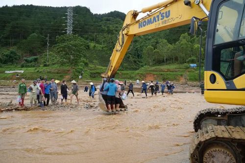 Lũ dần rút, người dân qua suối bằng máy xúc. (Ảnh: Nguyễn Oanh/TTXVN)
