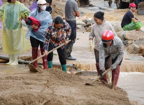Người dân quét dọn bùn đất sau lũ. (Ảnh: Nguyễn Oanh/ TTXVN)