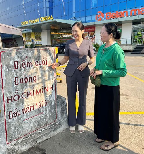 Phó Trưởng phòng Văn hóa - Xã hội phường Chơn Thành Trương Thị Bích Huệ (trái) giới thiệu với tác giả tấm bia di tích “Điểm cuối đường Hồ Chí Minh - đầu năm 1975”.