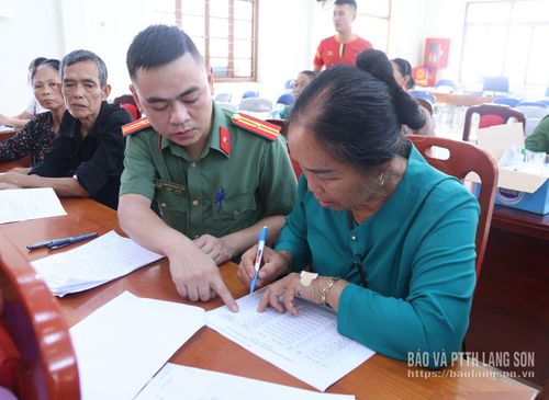 Cán bộ công an xã Tân Đoàn hướng dẫn thân nhân liệt sỹ điền thông tin trên phiếu